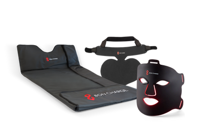 Glow Boost Kit Bundle, including neck and chest mask, sauna blanket and red light face mask switched on glowing red.