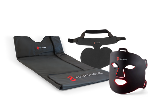 Glow Boost Kit Bundle, including neck and chest mask, sauna blanket and red light face mask switched on glowing red.
